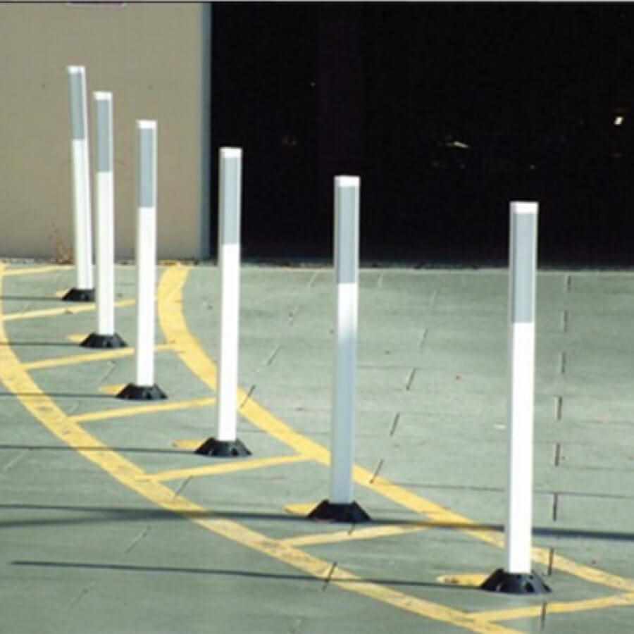 Row of white flexible traffic delineator posts guiding lane curve
